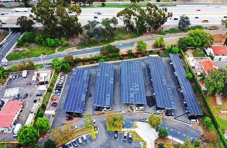 A drone shot of a parking lot with five solar panel roofs.